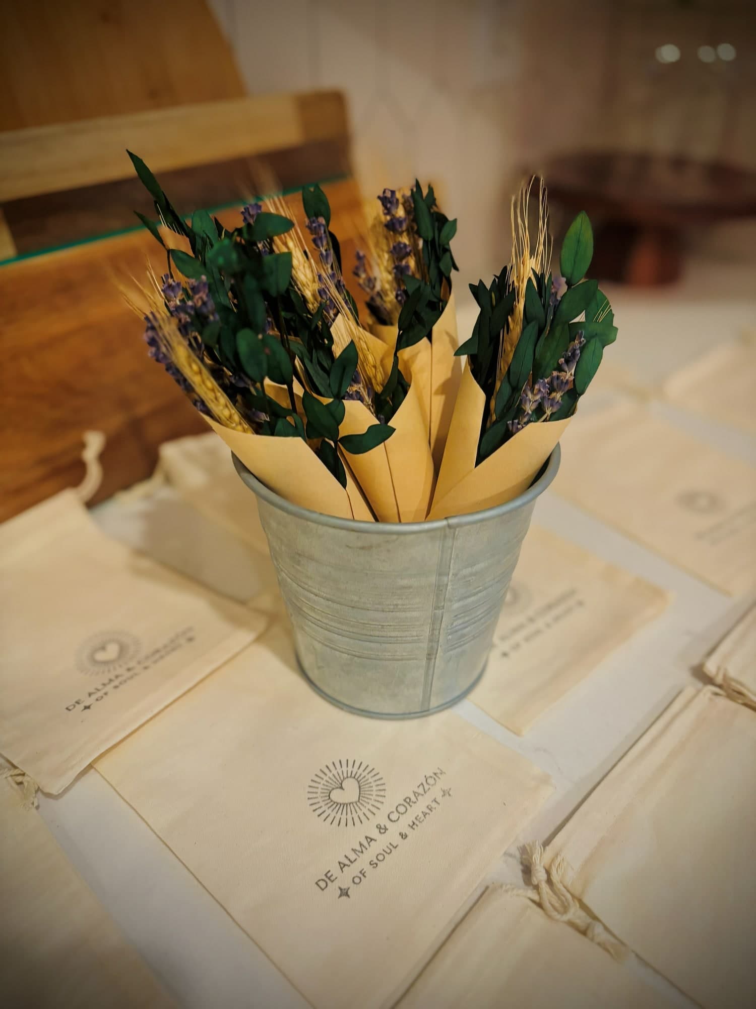 Small dried bouquets of lavender, wheat and greenery wrapped in paper cones, in a tin bucket on cotton De Alma y Corazón bags
